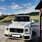A luxurious Mercedes-Benz G-Class SUV parked in a picturesque outdoor setting, showcasing an elegant design and scenic mountain backdrop.